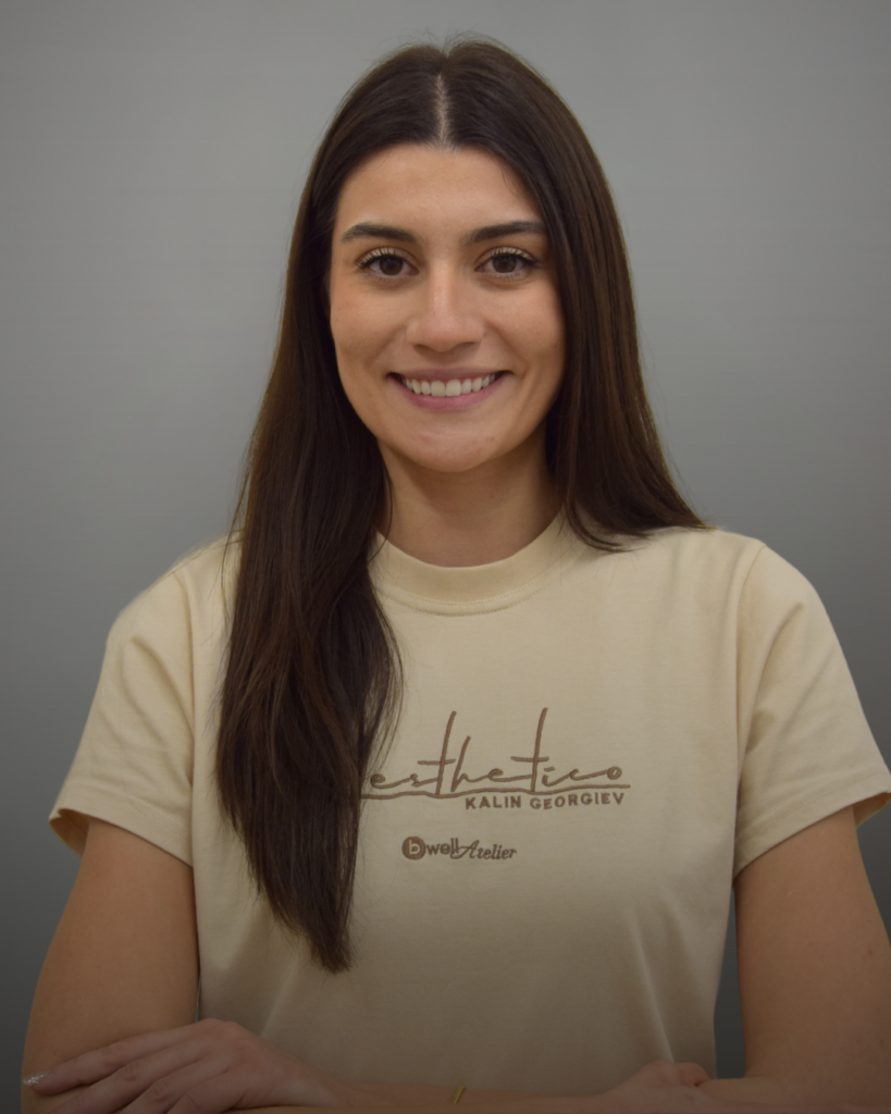 Портрет на лекар по дентална медицина с тъмна коса и тениска с лого Aesthetico, на сив фон.